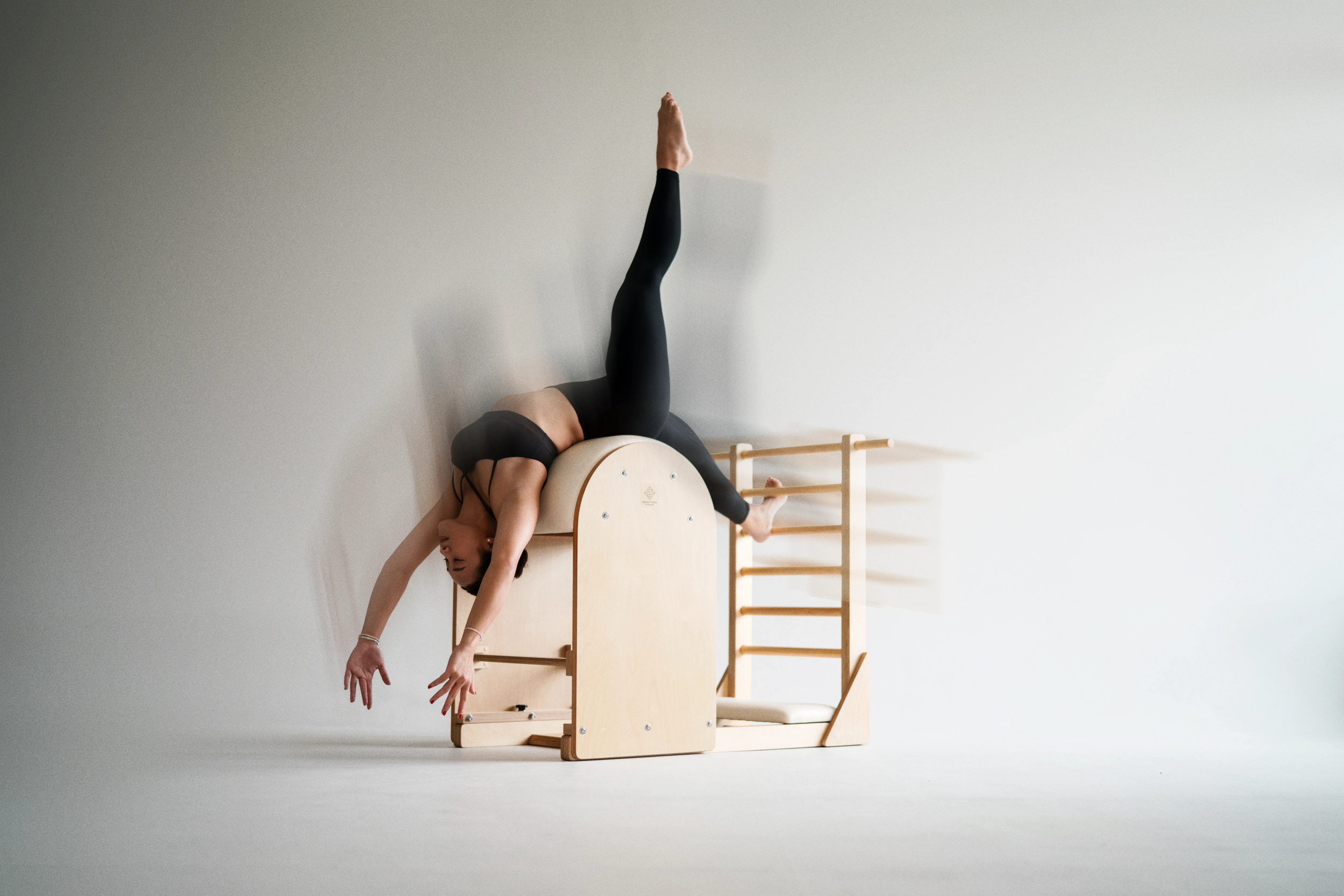 Person moving through a supported Pilates ladder barrel back extension in a calm studio.