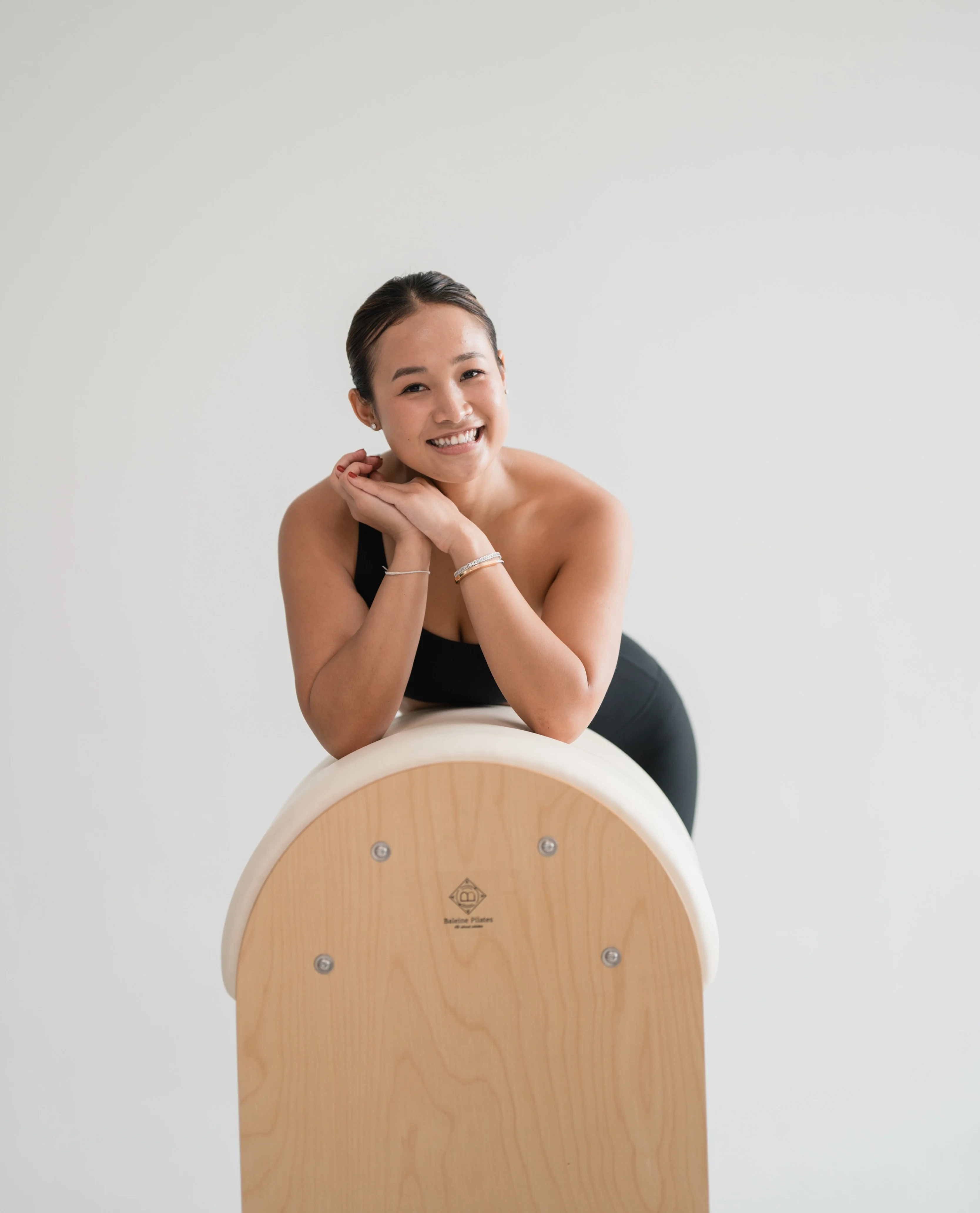 Emily, founder of Core Community, leaning on Pilates equipment in a calm studio portrait.